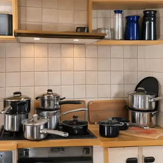 A kitchen with pots, pans, a stove, and a cutting board but 