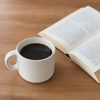 A coffee mug next to an open book on a desk
