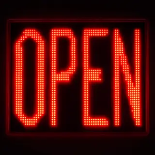 The word 'OPEN' displayed on a red LED sign with glowing pix
