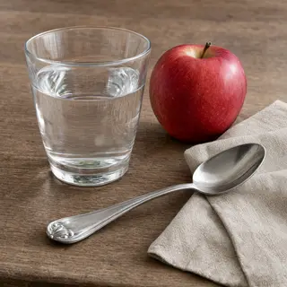A still life on a wooden table featuring a clear glass of wa