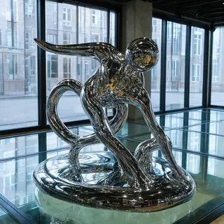 A chrome sculpture in a room with a glass floor and large wi