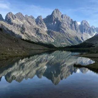 A mountain range reflected in a still alpine lake, with the 