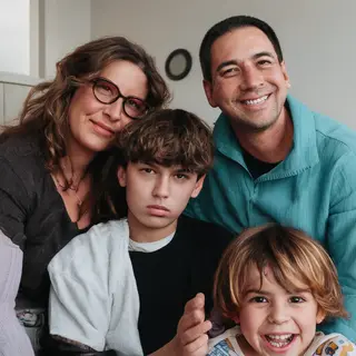 A family photo with four people: a father beaming with pride
