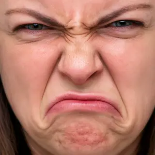 A close-up of a person's face showing clear disgust, nose wr