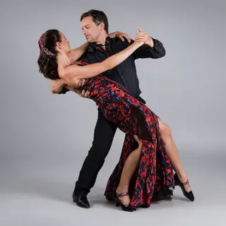 Two tango dancers in a close embrace, the man dipping the wo