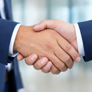 Two people shaking hands in a professional setting, all fing