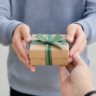 One person handing a small gift box to another person, both 