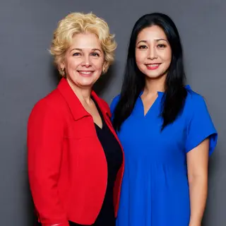 Two women standing side by side: one with short blonde hair 
