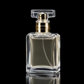 A clear glass perfume bottle on a reflective black surface w