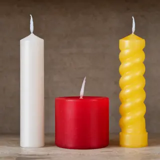 A tall thin white candle, a short fat red candle, and a medi