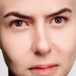 A human face with eyes, nose, and mouth but no eyebrows