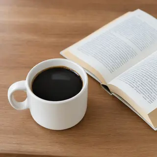 A coffee mug next to an open book on a desk