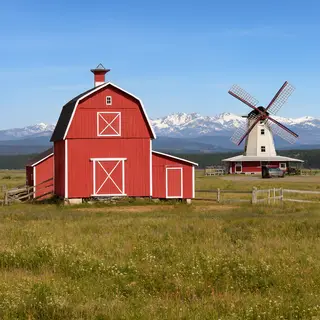 A landscape with a red barn in the foreground at large scale