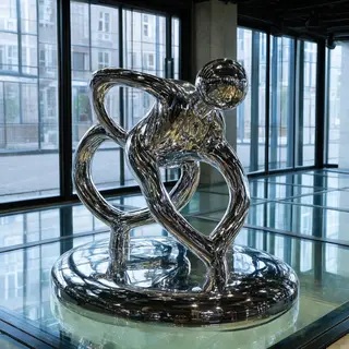 A chrome sculpture in a room with a glass floor and large wi