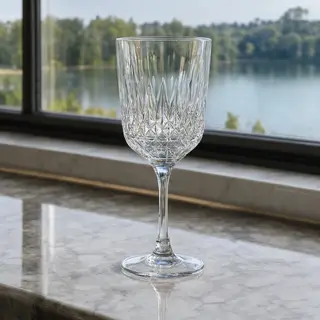 A crystal wine glass on a polished marble counter next to a 
