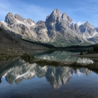 A mountain range reflected in a still alpine lake, with the 
