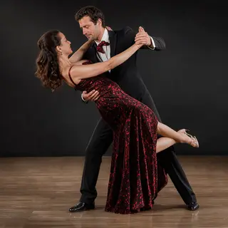 Two tango dancers in a close embrace, the man dipping the wo