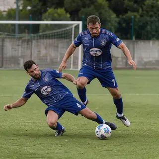 Two soccer players mid-tackle, one sliding and the other jum