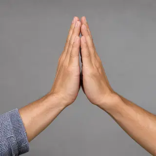 Two people doing a high-five, palms meeting with all fingers