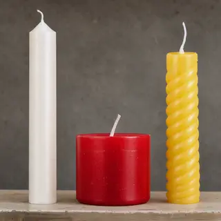 A tall thin white candle, a short fat red candle, and a medi