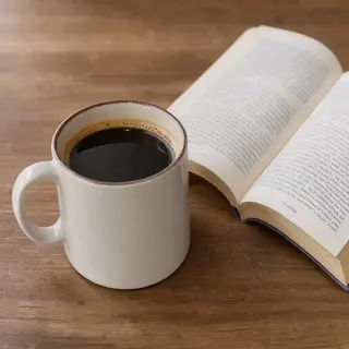 A coffee mug next to an open book on a desk