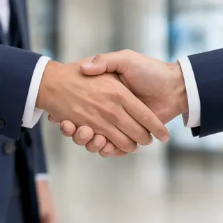 Two people shaking hands in a professional setting, all fing