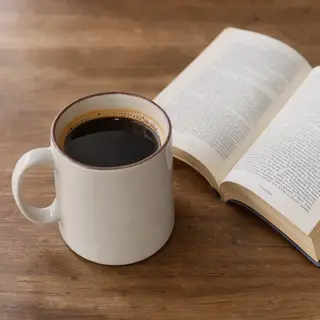 A coffee mug next to an open book on a desk