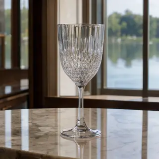 A crystal wine glass on a polished marble counter next to a 