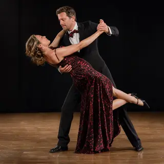 Two tango dancers in a close embrace, the man dipping the wo