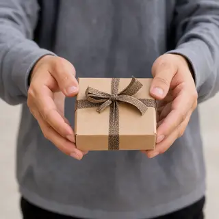 One person handing a small gift box to another person, both 