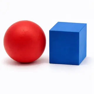A red ball and a blue cube sitting side by side on a white s