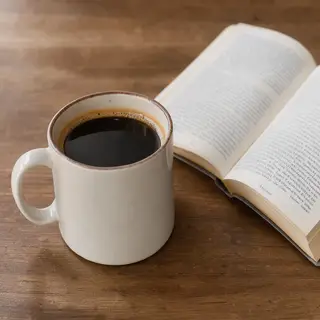 A coffee mug next to an open book on a desk