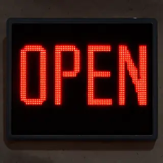 The word 'OPEN' displayed on a red LED sign with glowing pix