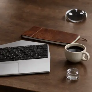 A workspace desk with a brushed aluminum laptop, a leather-b