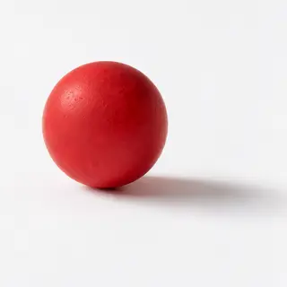 A red sphere on a white surface with a single shadow cast to