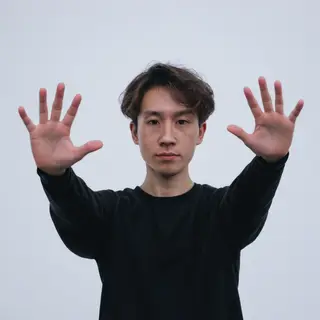 A person standing with both hands visible at their sides, fi