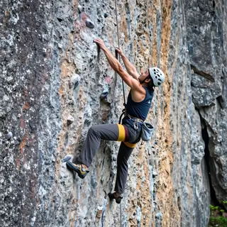 A rock climber clinging to a cliff face with arms and legs e