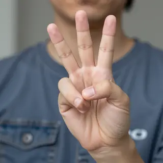 A person making a peace sign with their right hand, clearly 