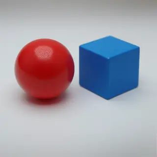 A red ball and a blue cube sitting side by side on a white s