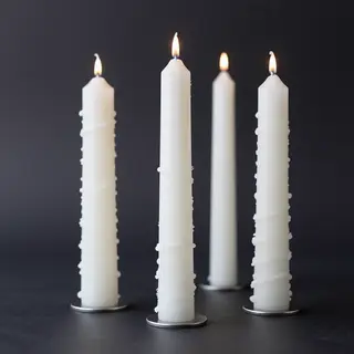 Exactly 4 white candles standing on a dark surface