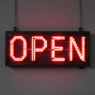 The word 'OPEN' displayed on a red LED sign with glowing pix