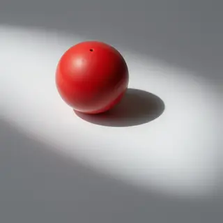 A red sphere on a white surface with a single shadow cast to