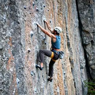 A rock climber clinging to a cliff face with arms and legs e