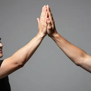 Two people doing a high-five, palms meeting with all fingers