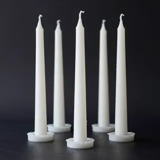 Exactly 4 white candles standing on a dark surface
