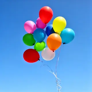 Exactly 11 colorful balloons floating against a clear blue s