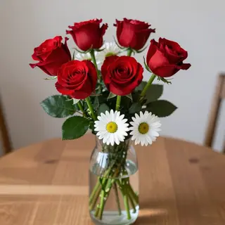 4 red roses and 2 white daisies in a glass vase on a table