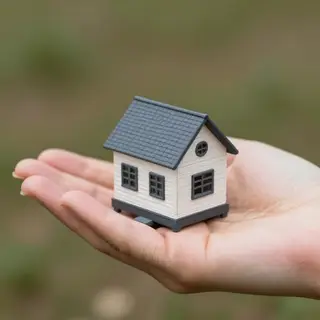 A miniature house sitting on the palm of someone's hand