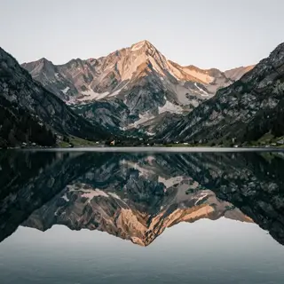 A mountain range reflected in a still alpine lake, with the 
