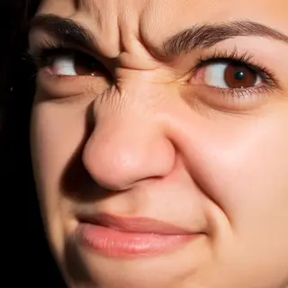 A close-up of a person's face showing clear disgust, nose wr